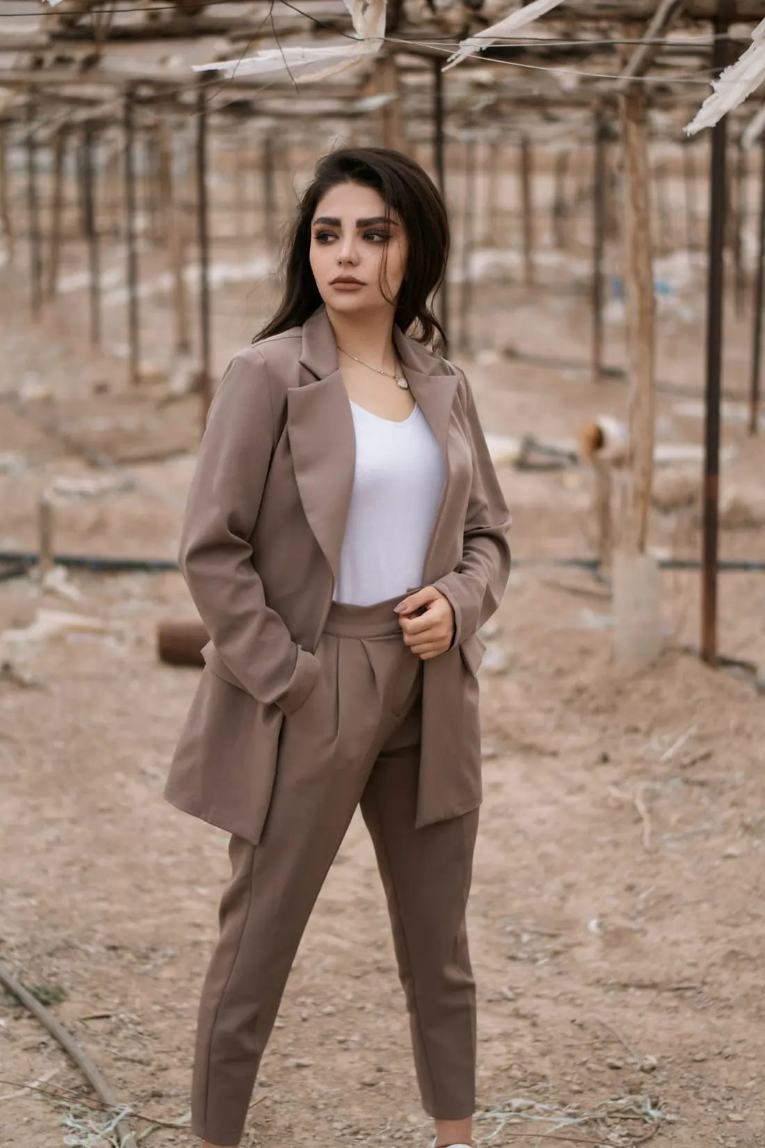 A woman in a taupe blazer and matching trousers on a dry hillside
