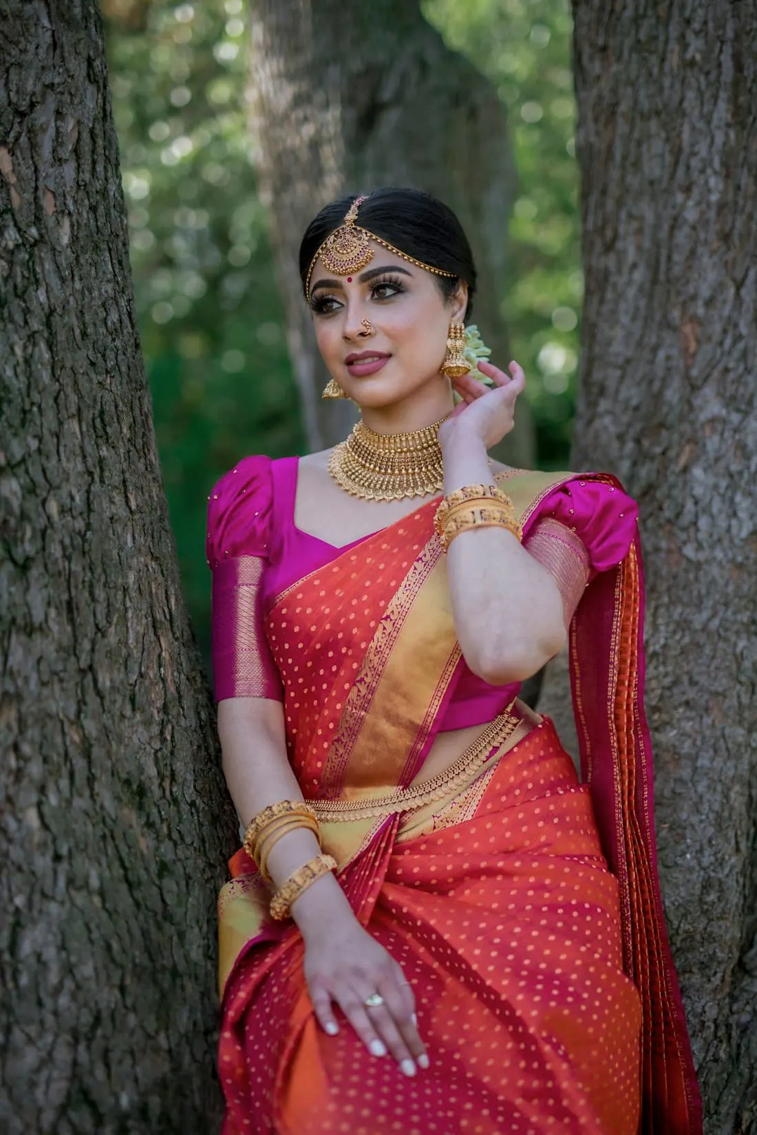 A woman in an orange Kanjivaram saree with a pink blouse
