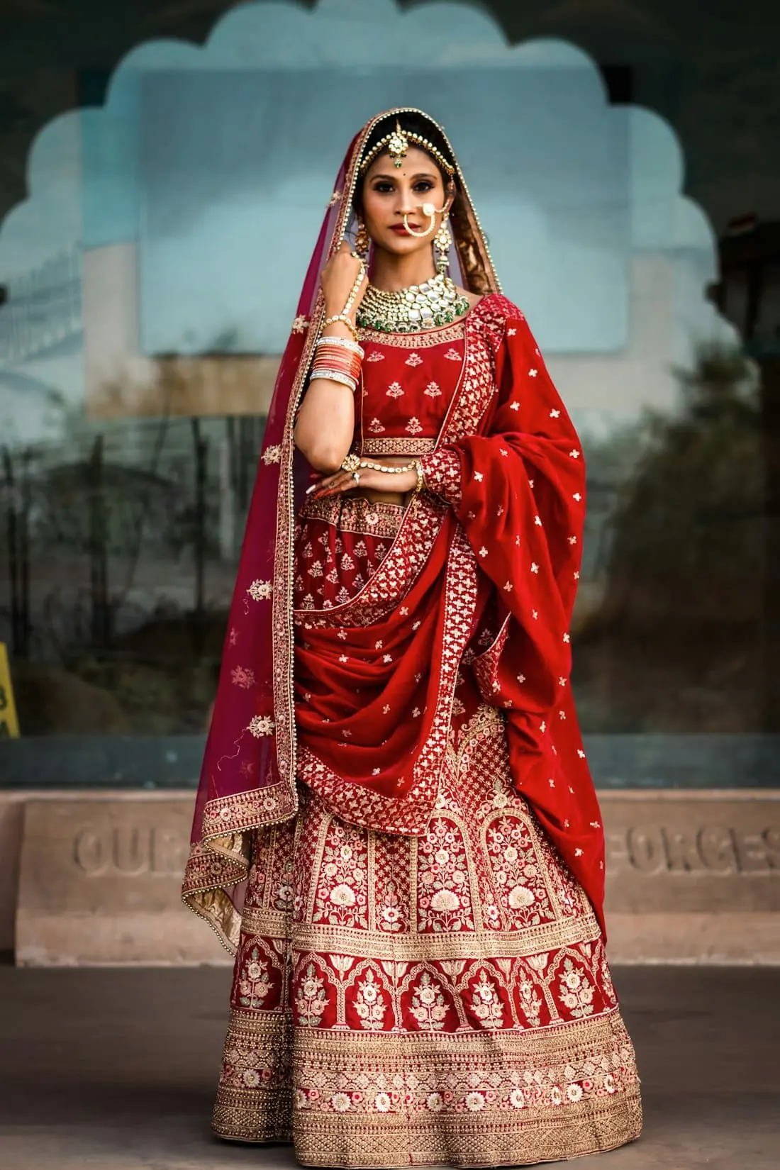 A bride in a red and gold lehenga with a long veil