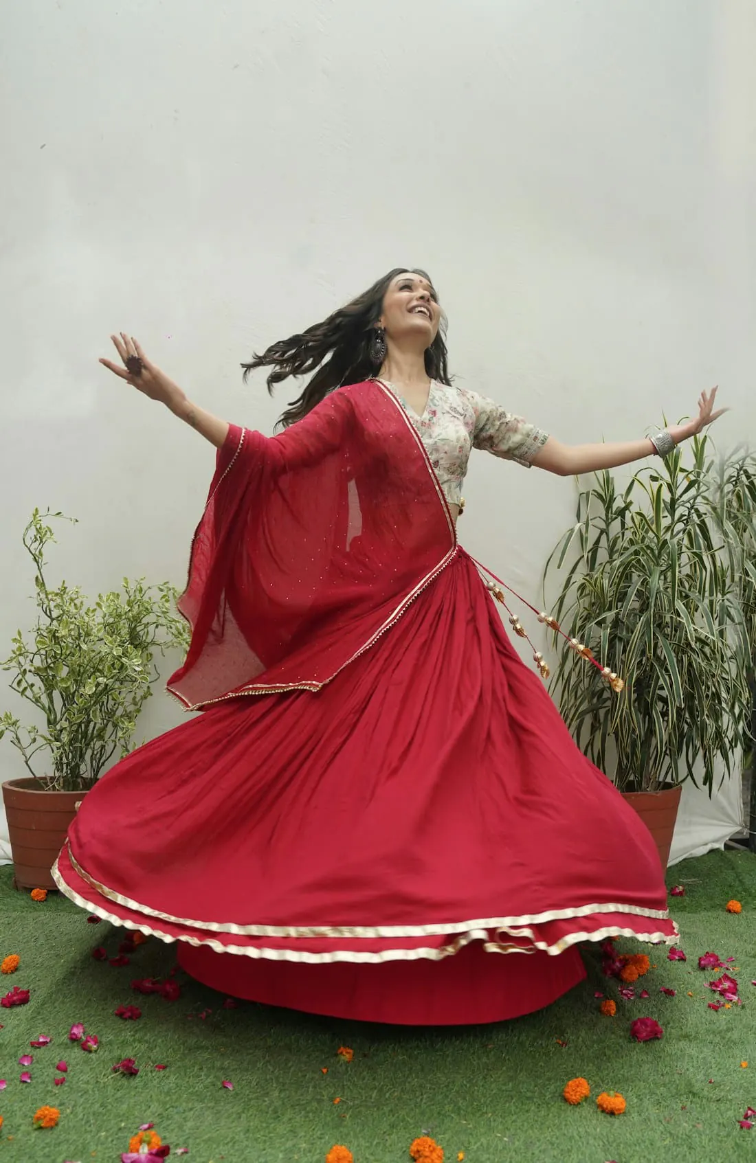 A woman twirling in a crimson anarkali with a flowing dupatta