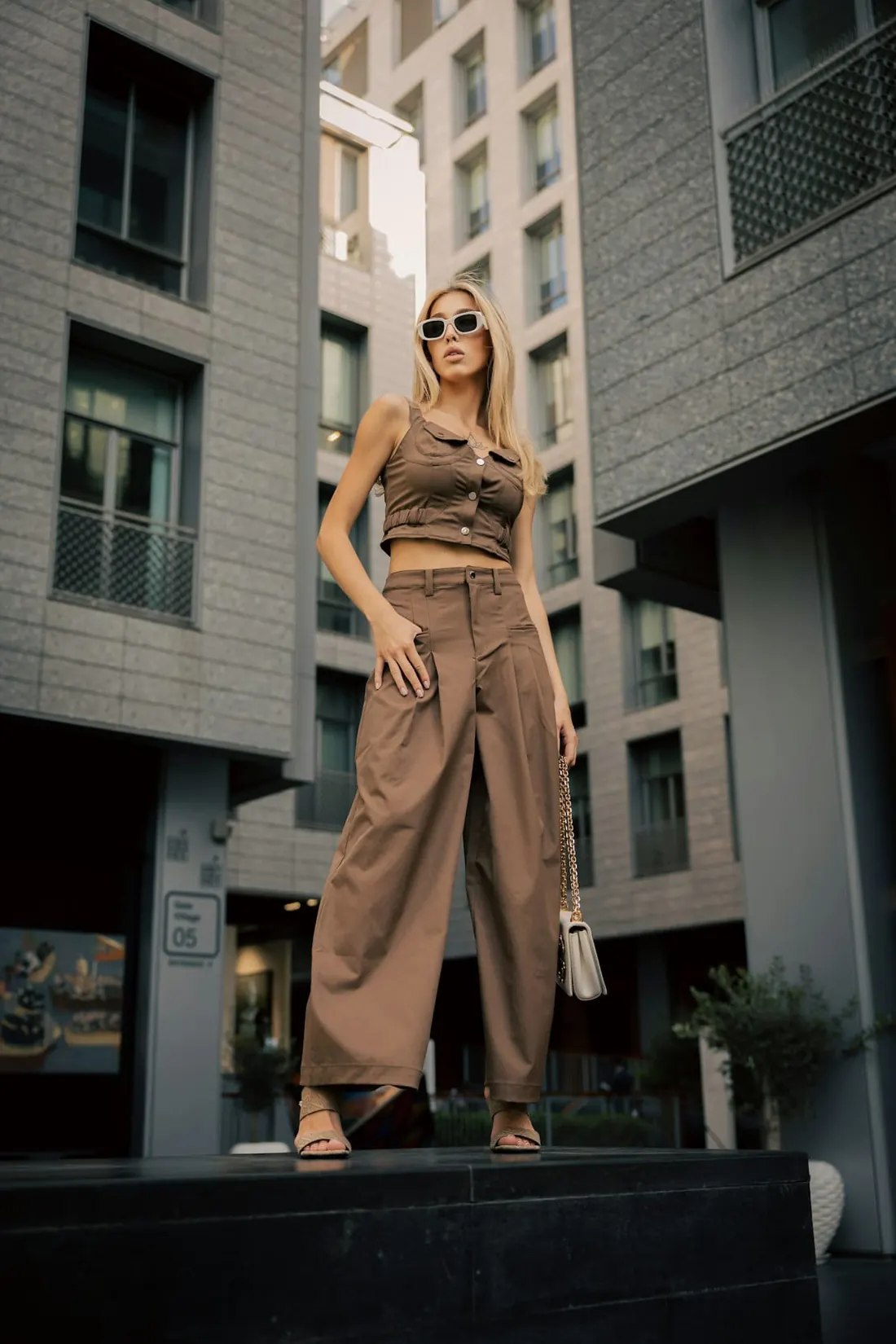 A woman in wide-leg camel trousers and a matching top on a city street